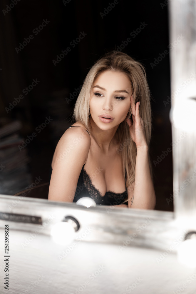 Model elegant young woman with a beautiful body with a breast in a lace  black bra in a dark bedroom near white mirror. Amazing sexy blonde girl.  Stock Photo | Adobe Stock