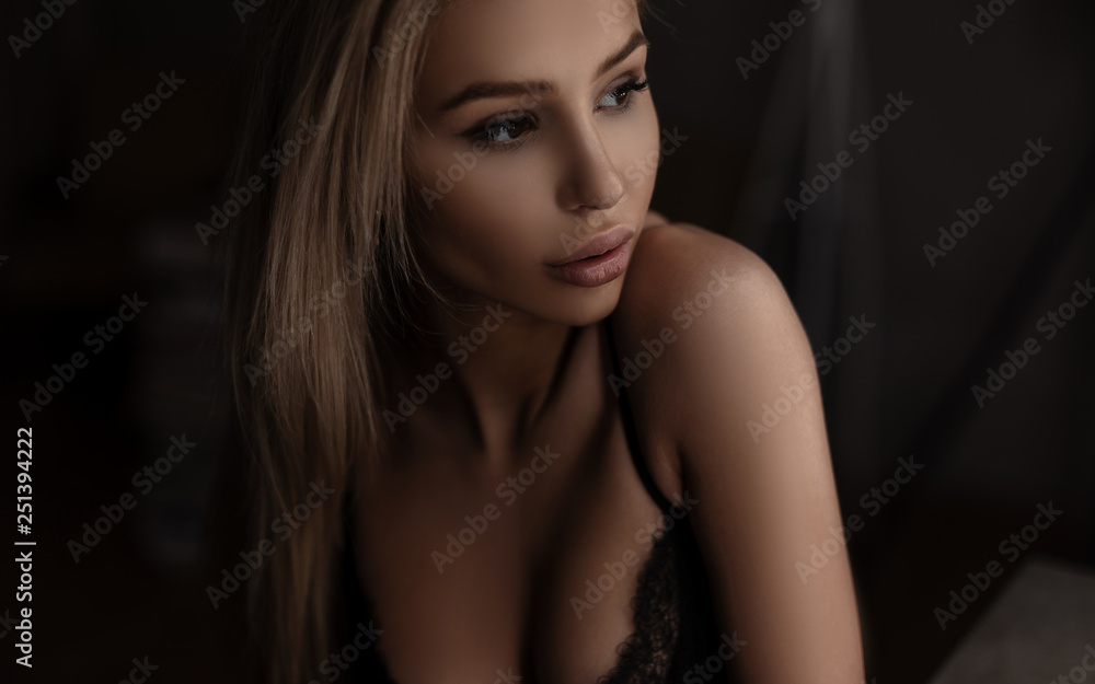 Foto de Pretty cute young woman model with beautiful breasts in a chic bra  with sexy lips in a dark bedroom. Portrait of a sensual attractive girl. do  Stock