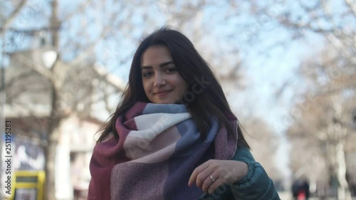 Happy girl in a fancy scarf smartening up cheerily in street in winter in slo-mo   photo