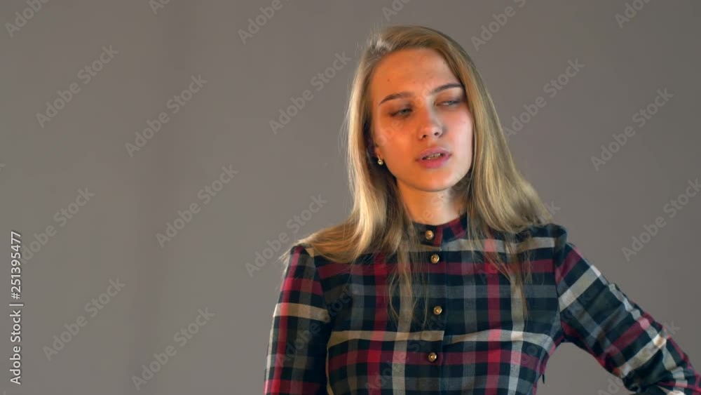Young blonde girl in plaid dress with beautiful hair and full lips reads messages on smartphone. Woman changes in face showing her emotions. Simple beauty. Tender emotions and coquetry Young blonde girl in plaid dress with beautiful hair and full lips reads messages on smartphone. Woman changes in face showing her emotions. Simple beauty. Tender emotions and coquetry