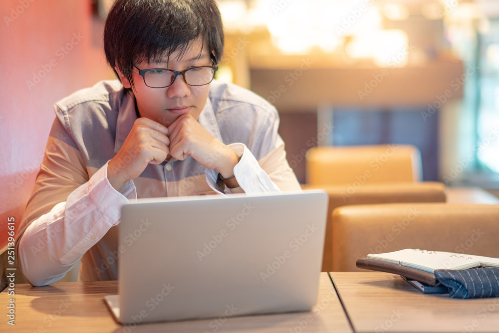 Asian businessman using laptop computer in the cafe thinking about business work solution. Smart working with online social network. Internet of things concepts Asian businessman using laptop computer in the cafe thinking about business work solution. Smart working with online social network. Internet of things concepts
