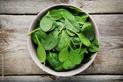 Spinach leafs in bowl on grey wooden table