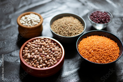 Assortment of legumes: beans and lentils. Raw healthy food. Vegetable protein. Dark background. Close up. Space for text