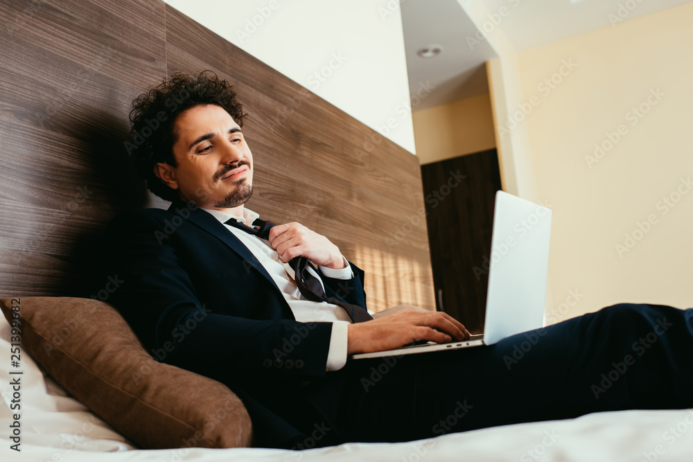 tired businessman in suit working on laptop in hotel room tired businessman in suit working on laptop in hotel room