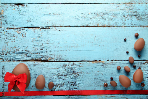 Chocolate easter eggs with red ribbon on blue wooden table