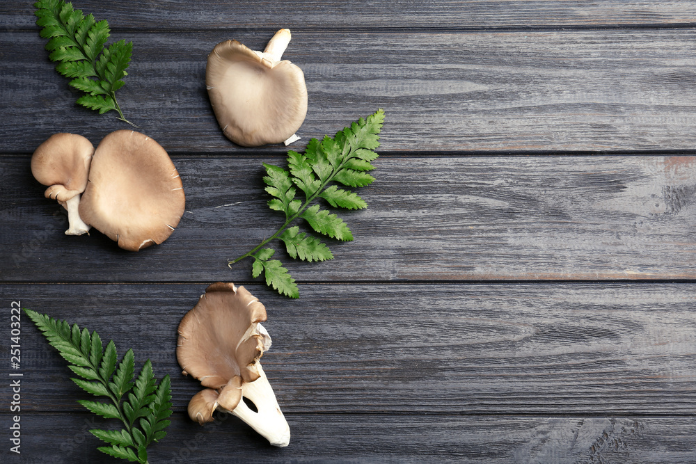 Flat lay composition with oyster mushrooms and leaves on wooden background, space for text