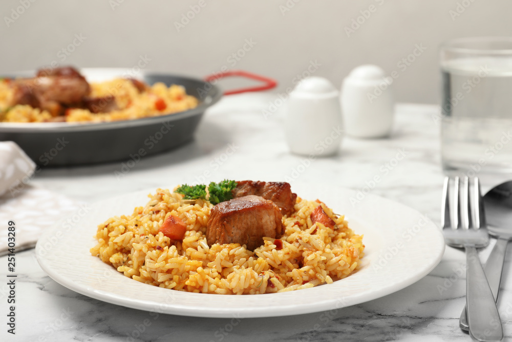 Plate of tasty rice pilaf with meat on table