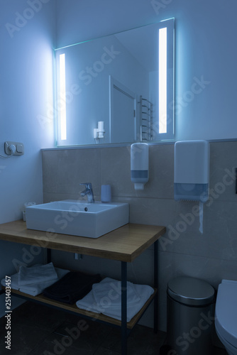 hotel bathroom with washstand and towels with neon light on mirror