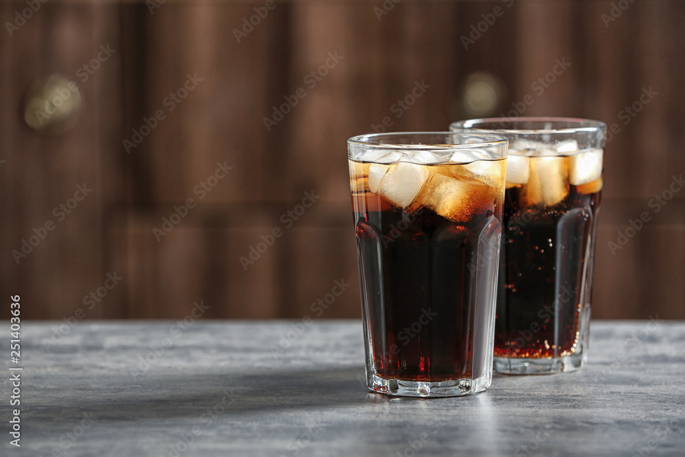 Glasses of cold cola on table against blurred background. Space for text Glasses of cold cola on table against blurred background. Space for text