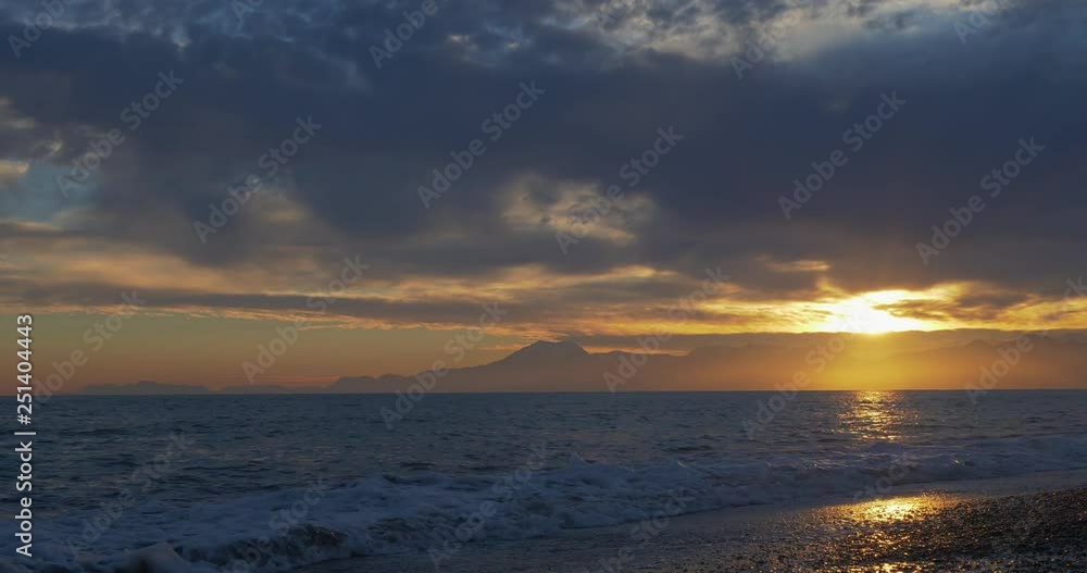Beautiful sunset at beach with golden sun reflection on the sea and mountain background Beautiful sunset at beach with golden sun reflection on the sea and mountain background