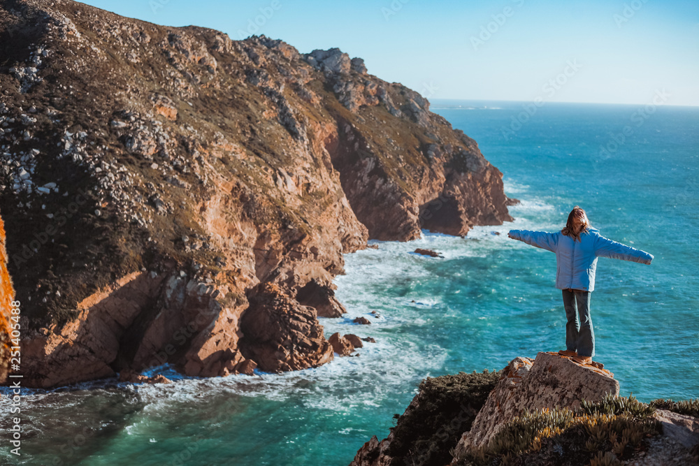 Woman relaxing on rocky cliff Cabo da Roca, Portuga