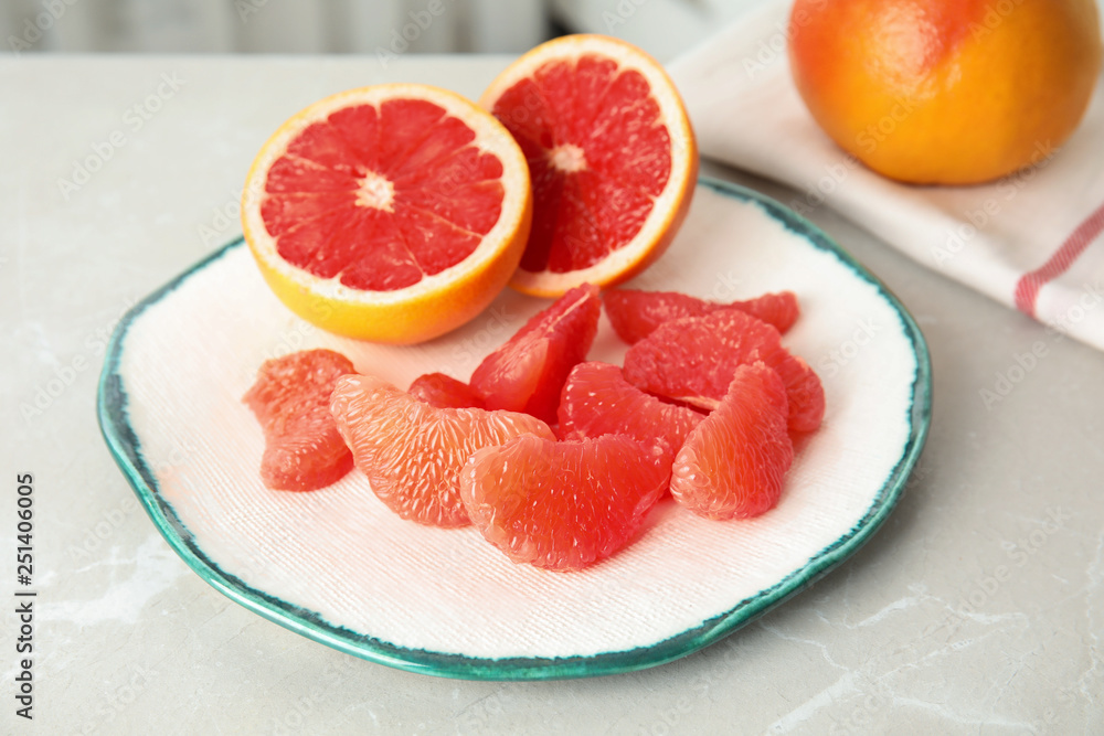 Plate with yummy grapefruits on grey table