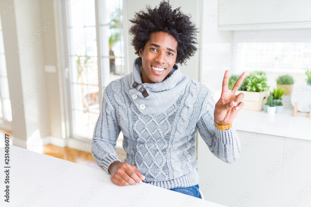 African American man wearing winter sweater smiling with happy face winking at the camera doing victory sign. Number two. African American man wearing winter sweater smiling with happy face winking at the camera doing victory sign. Number two.