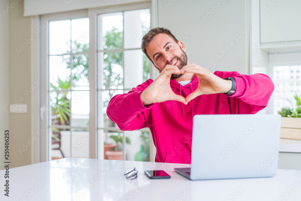 Handsome man working using computer laptop smiling in love showing heart symbol and shape with hands. Romantic concept. Handsome man working using computer laptop smiling in love showing heart symbol and shape with hands. Romantic concept.