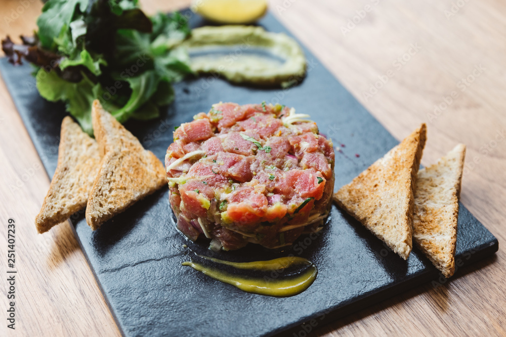 Spicy Bluefin Tuna Tartare with sour and spicy sauce. Served with toast and salad on black stone plate. Spicy Bluefin Tuna Tartare with sour and spicy sauce. Served with toast and salad on black stone plate.