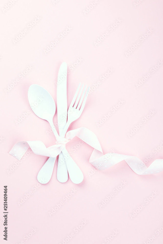Festive table setting with fork, knife and hearts  on pink pastel background.Romantic dinner. Space for text. Top view.