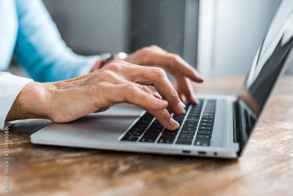 partial view of senior woman typing on laptop at home partial view of senior woman typing on laptop at home