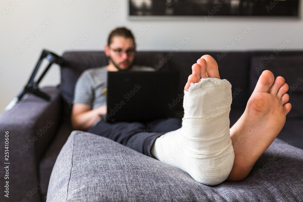 Obraz premium man with a broken leg is surfing the internet