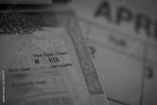 H1B visa (for specialty workers) stamp in passport, blurred april calendar on background. H1B visa program deadline concept. Close up view. Black and white photo. photo