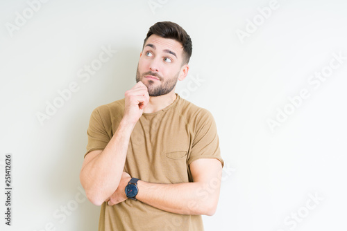 Young handsome man over isolated background with hand on chin thinking about question, pensive expression. Smiling with thoughtful face. Doubt concept.