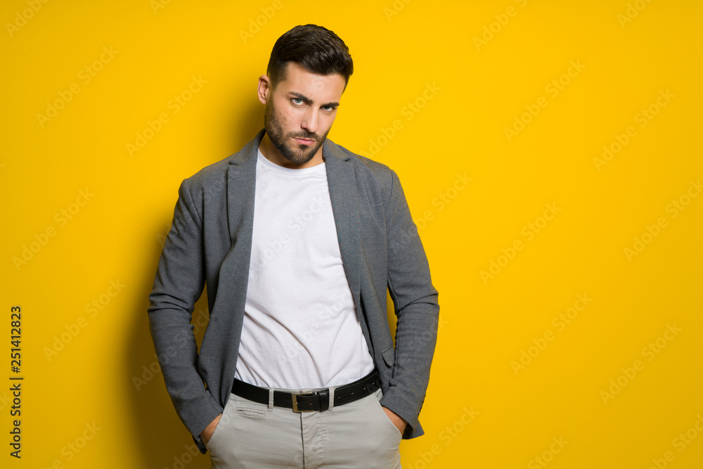 Fototapeta premium Young handsome man possing and modeling over yellow isolated background