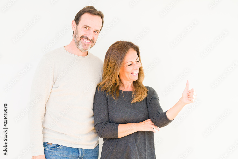 Beautiful middle age couple in love over isolated background Looking proud, smiling doing thumbs up gesture to the side Beautiful middle age couple in love over isolated background Looking proud, smiling doing thumbs up gesture to the side