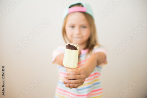 Cute little girl shows ice cream on a stick. Selective focus