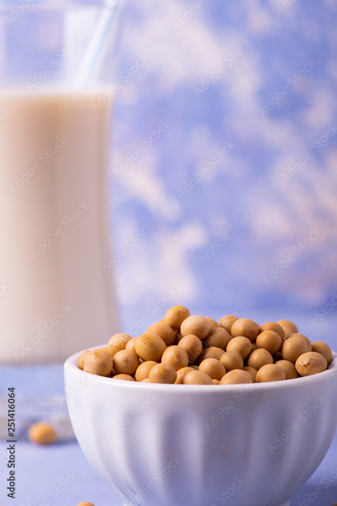a bowl in the foreground with yellow soy, on the background bottle with soy milk a bowl in the foreground with yellow soy, on the background bottle with soy milk