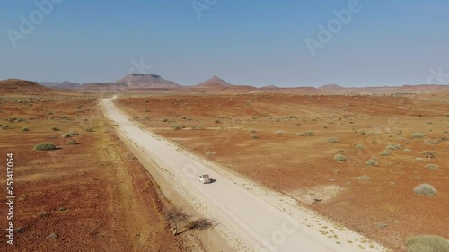 4x4 offroad vehicle driving through arid desert landscape of Damaraland Namibia, Aerial drone shot