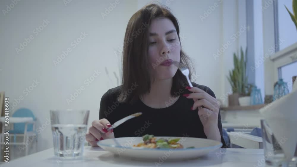 Portrait of a pretty young brunette girl eating in a beautiful restaurant or cafe. Portrait of a pretty young brunette girl eating in a beautiful restaurant or cafe.