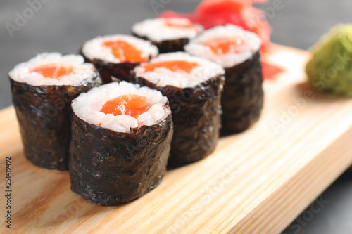 Tasty sushi rolls on wooden board, closeup. Food delivery