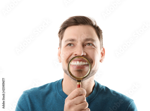 Smiling man with perfect teeth and magnifier on white background