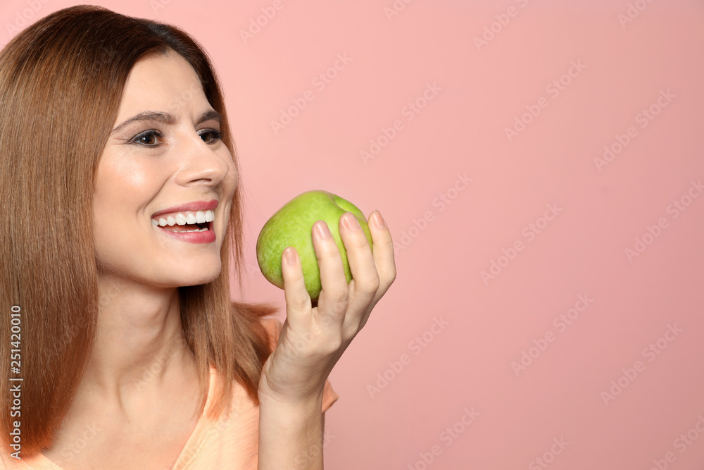 Smiling woman with perfect teeth and green apple on color background. Space for text Smiling woman with perfect teeth and green apple on color background. Space for text