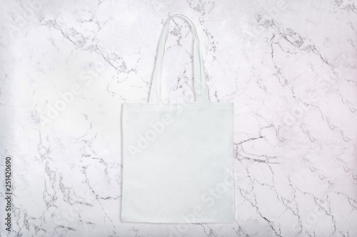 Flat lay of reusable white fabric bag on white natural marble texture as background