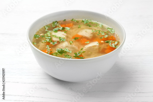 Bowl with fresh homemade chicken soup on wooden table