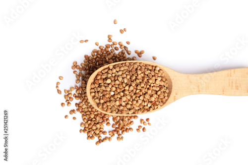 Spoon with uncooked buckwheat on white background, top view