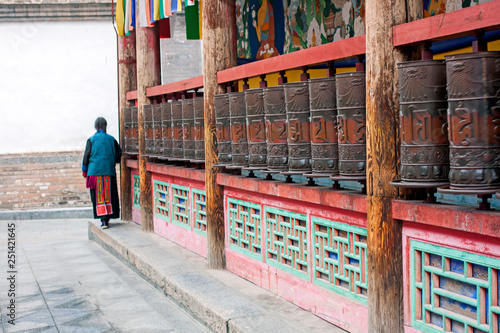 Woman Is Praying By Rotating Cylinders In Buddhist Temple.