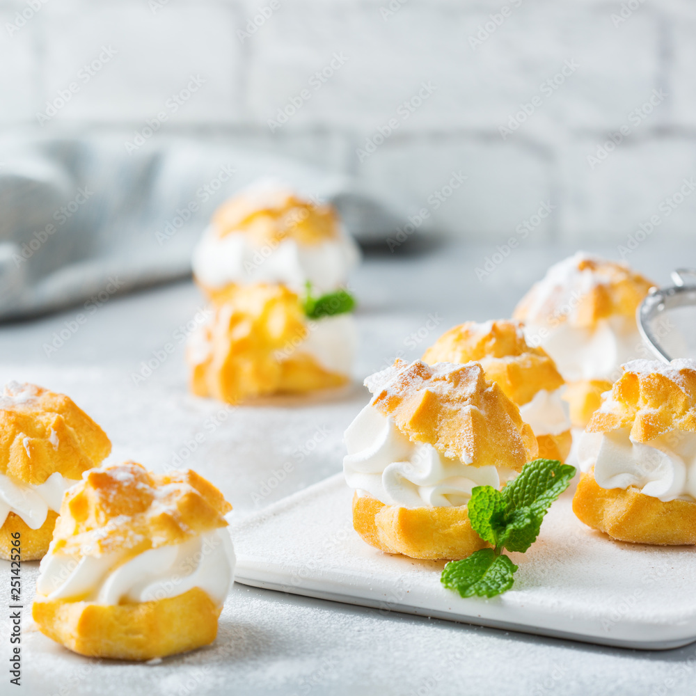 Delicious sweet profiteroles with cream on a modern kitchen table Delicious sweet profiteroles with cream on a modern kitchen table