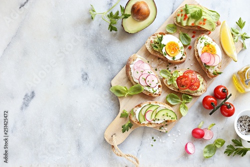 Photo Breakfast sandwich bread with avocado, egg, radishes and tomatoes