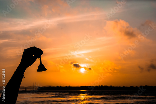 atardecer río Ganges en Varanasi, India. siluieta de mano tocando la campana, copy-space photo