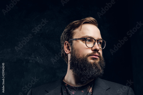 Portrait of a brutal hipster in glasses looking left on a black background in the studio