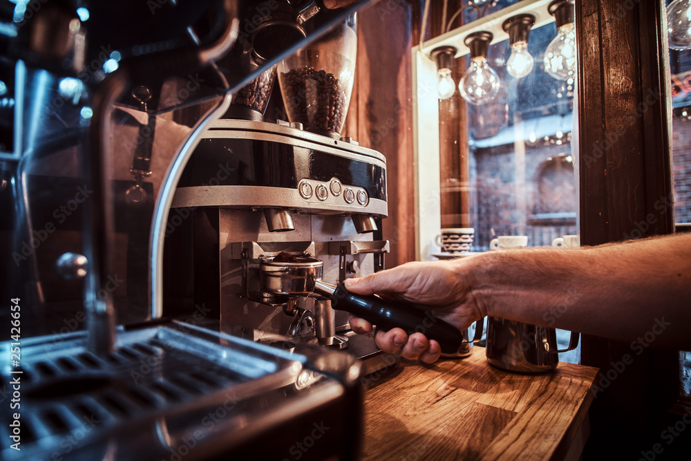 Barista hand holding a portafilter with a black ground coffee in a cafe shop or restaurant