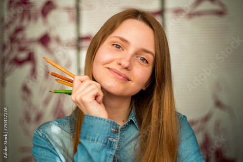 Close-up portrait of a beautiful excited woman drowing with pencils amd smiling 