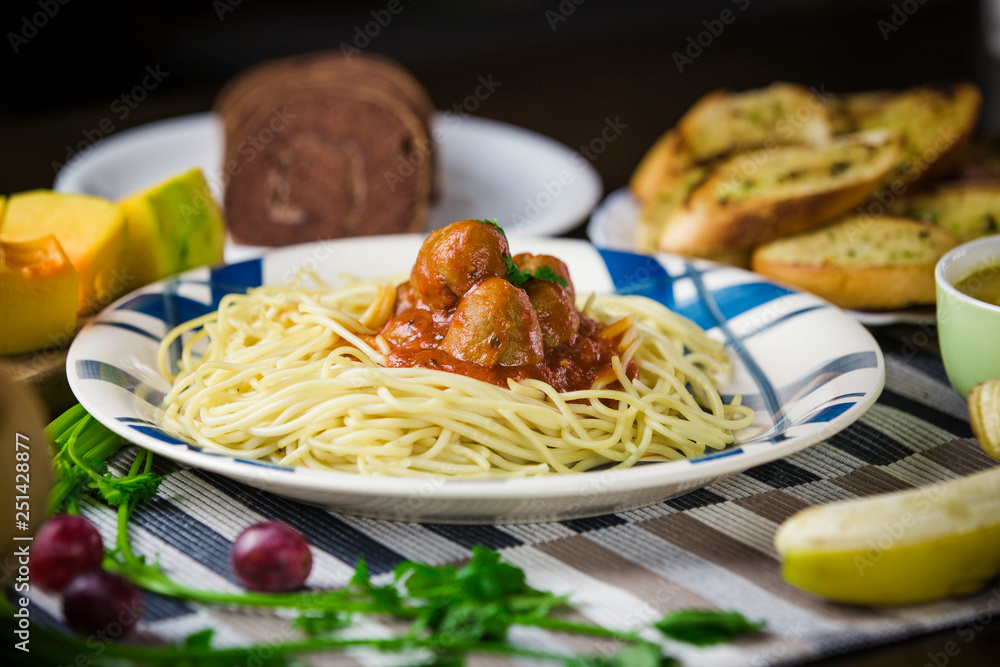 Spaghetti with meatballs in tomato sauce and fresh fruits