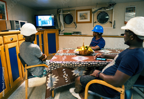 Seamen crew onboard a ship or vessel having fun watching TV. Recreation during at sea photo