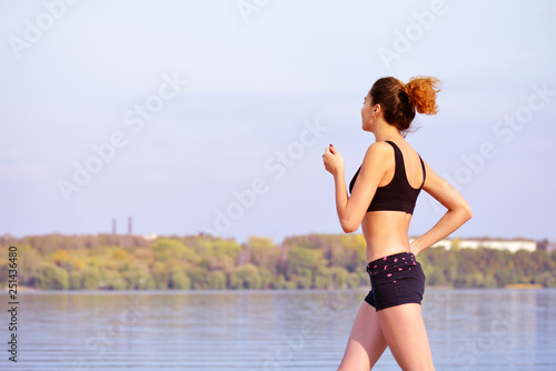 Running woman. Female runner jogging during outdoor workout on beach. Sport model outdoors. Fitness Concept.