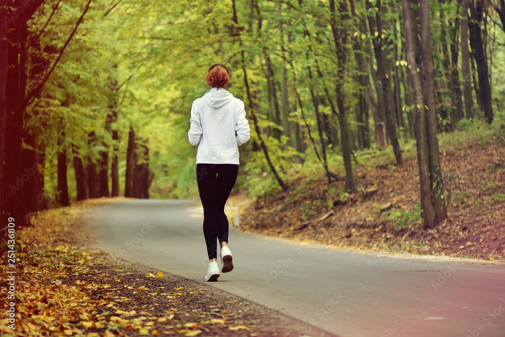 Fototapeta premium Running woman. Female runner jogging during outdoor workout in forest. Sport model outdoors. Fitness Concept.