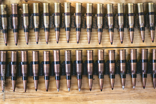 machine gun ammo on a wooden table, bullet belt, bandoleer, chain of ammo on wooden background,cartridge 7.62 mm caliber, top view photo