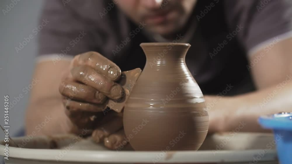 Close up of Potter creates product on potter's wheel or on potter's lathe spinning pottery. Hands gently create correctly shaped handmade from clay Close up of Potter creates product on potter's wheel or on potter's lathe spinning pottery. Hands gently create correctly shaped handmade from clay