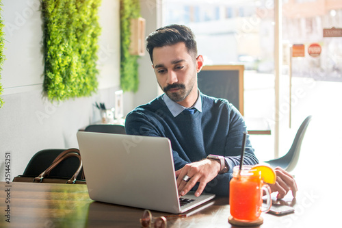 Handsome young man using laptop in a cafe